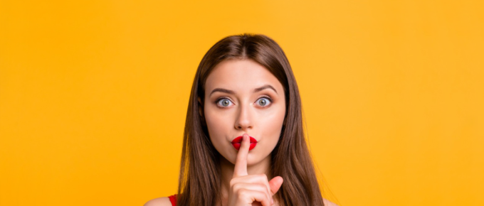 Woman with finger over lips in "be quiet" gesture