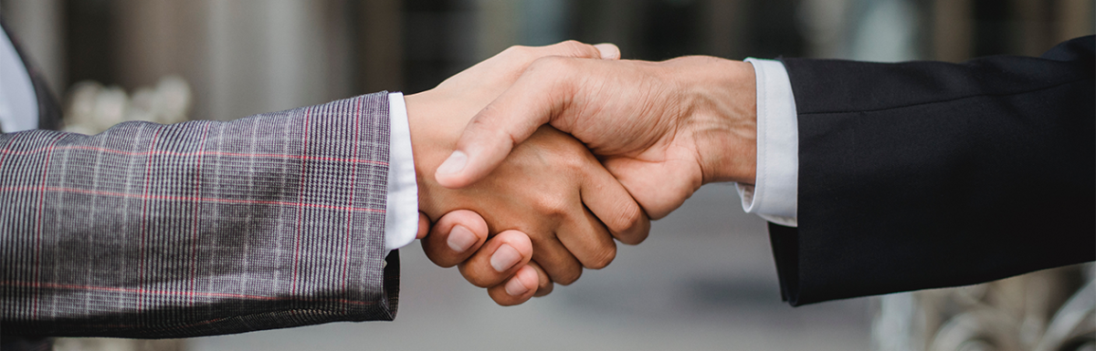 Close up of a handshake between two people wearing suits