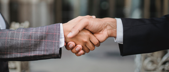 Close up of a handshake between two people wearing suits