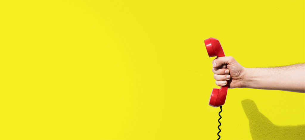 Hand Holding Red Phone On Bright Yellow Background
