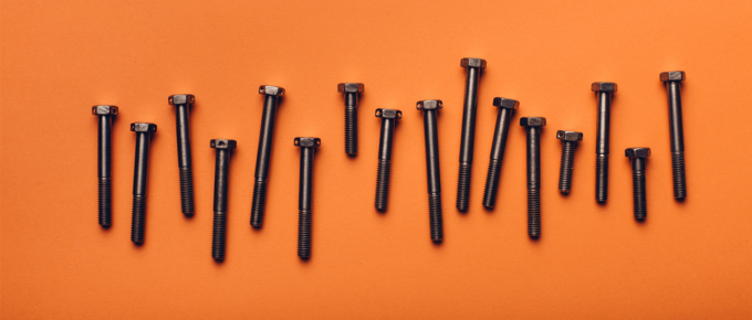 A row of black screws on an orange background