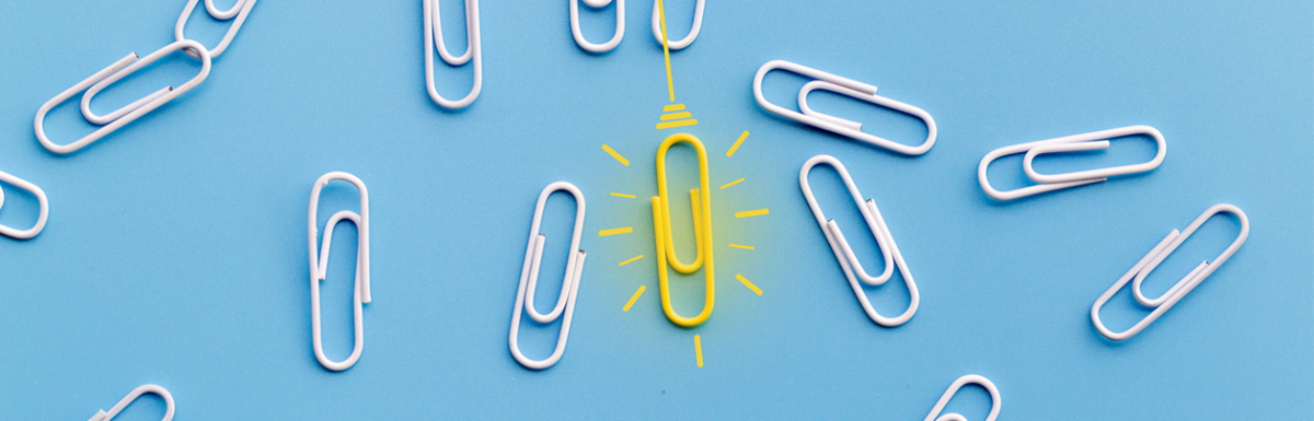 One yellow paperclip standing out among a group of white paperclips on a light blue background