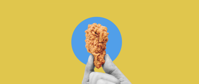 Hand holding Buffalo wing on a bright yellow background